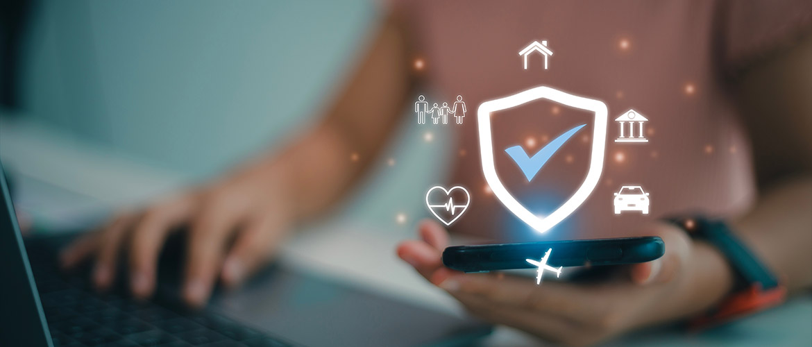 Une personne utilise un smartphone affichant un bouclier de sécurité numérique entouré d'icônes représentant la protection de la maison, de la famille, de la santé, des institutions et des véhicules, illustrant une solution globale de cybersécurité